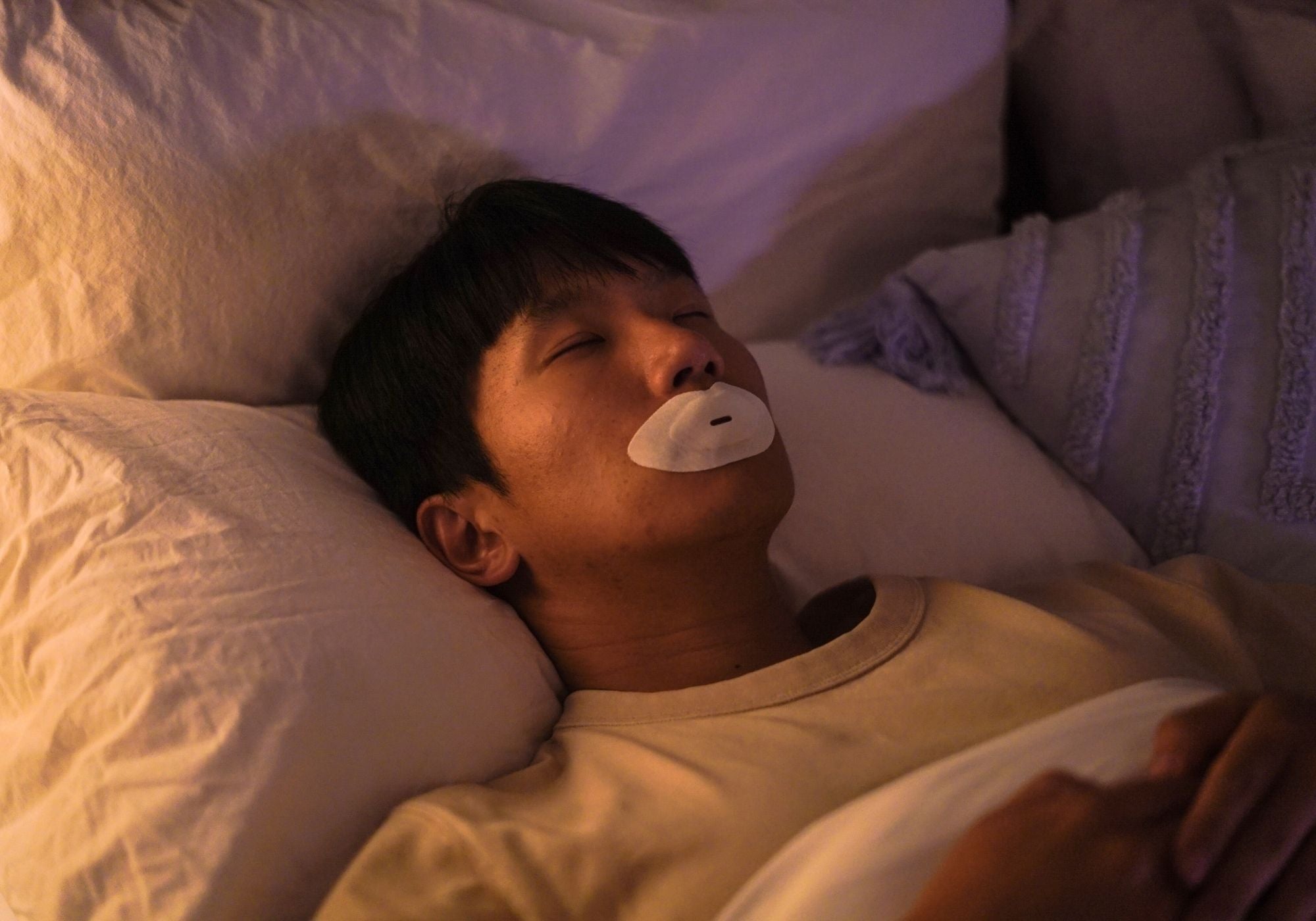 Man resting in bed wearing a Sayang Sleep Strip during the first night of a calming nasal breathing routine.